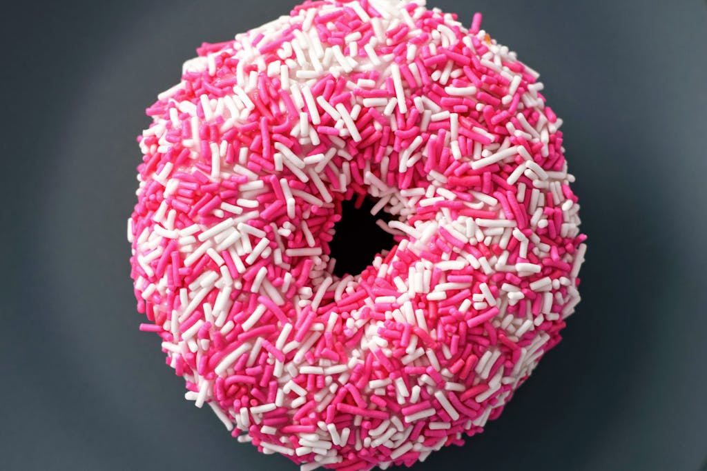 Close-up of a donut covered in pink and white sprinkles, perfect for sweet treat themes.