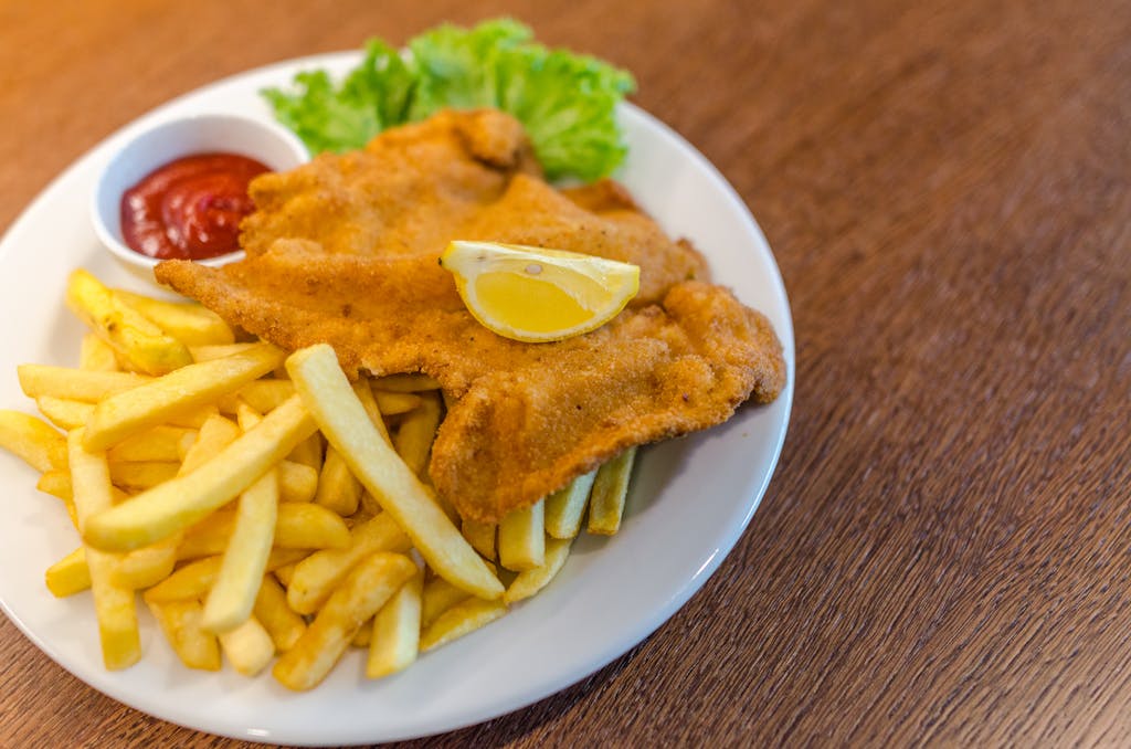 Delicious schnitzel served with crispy french fries, ketchup, and fresh lettuce on a plate.