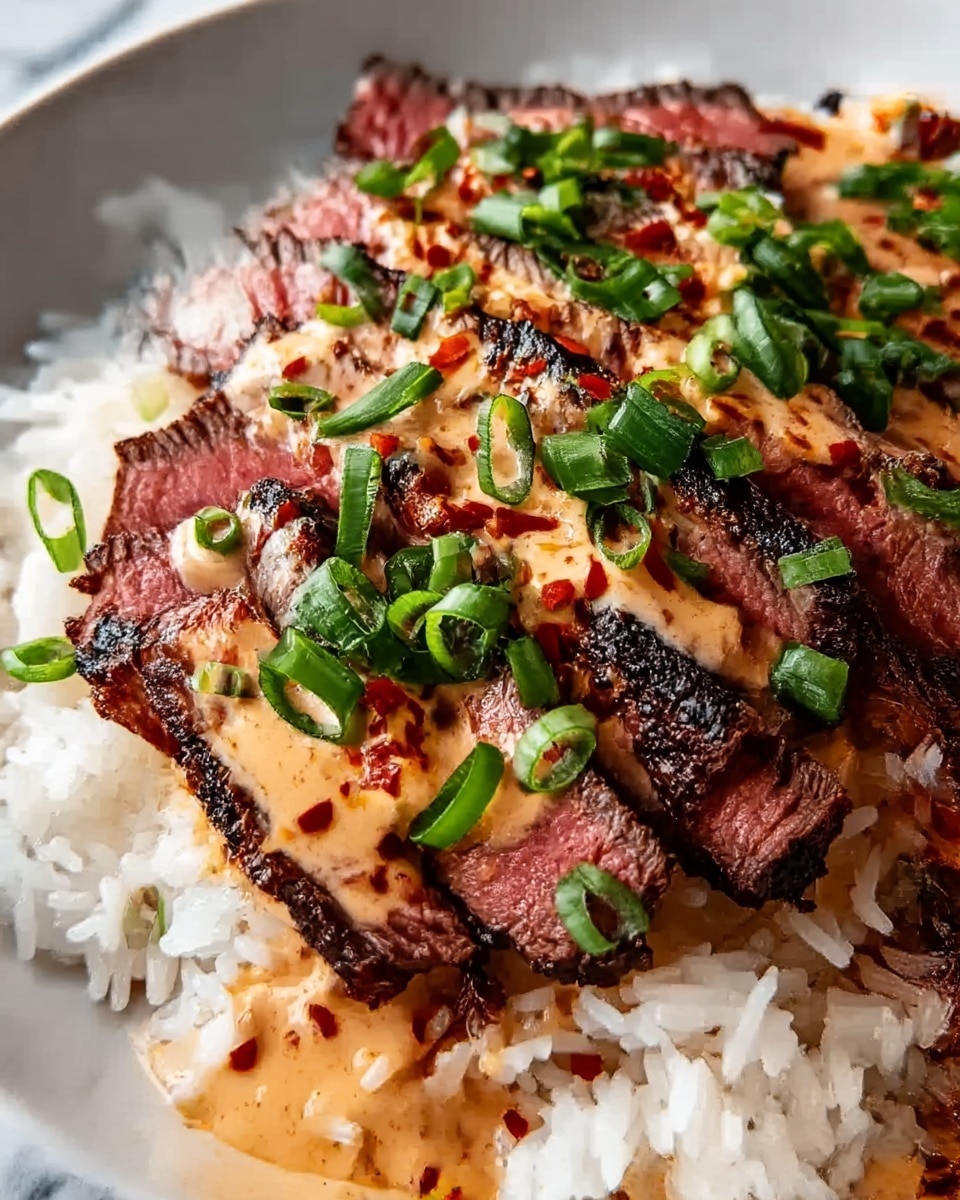 The image shows a dish with three main layers on a white plate placed on a white marbled surface. The bottom layer is white rice with a soft and slightly sticky texture. On top of the rice, there are thick slices of grilled steak with a dark charred outer edge and a pink center, arranged closely side by side. The steak is covered with a creamy orange sauce that looks smooth and slightly thick, sprinkled with a bit of red seasoning. Finally, the dish is topped with chopped green onions that add a fresh bright green color. Photo taken with an iphone --ar 4:5 --v 7